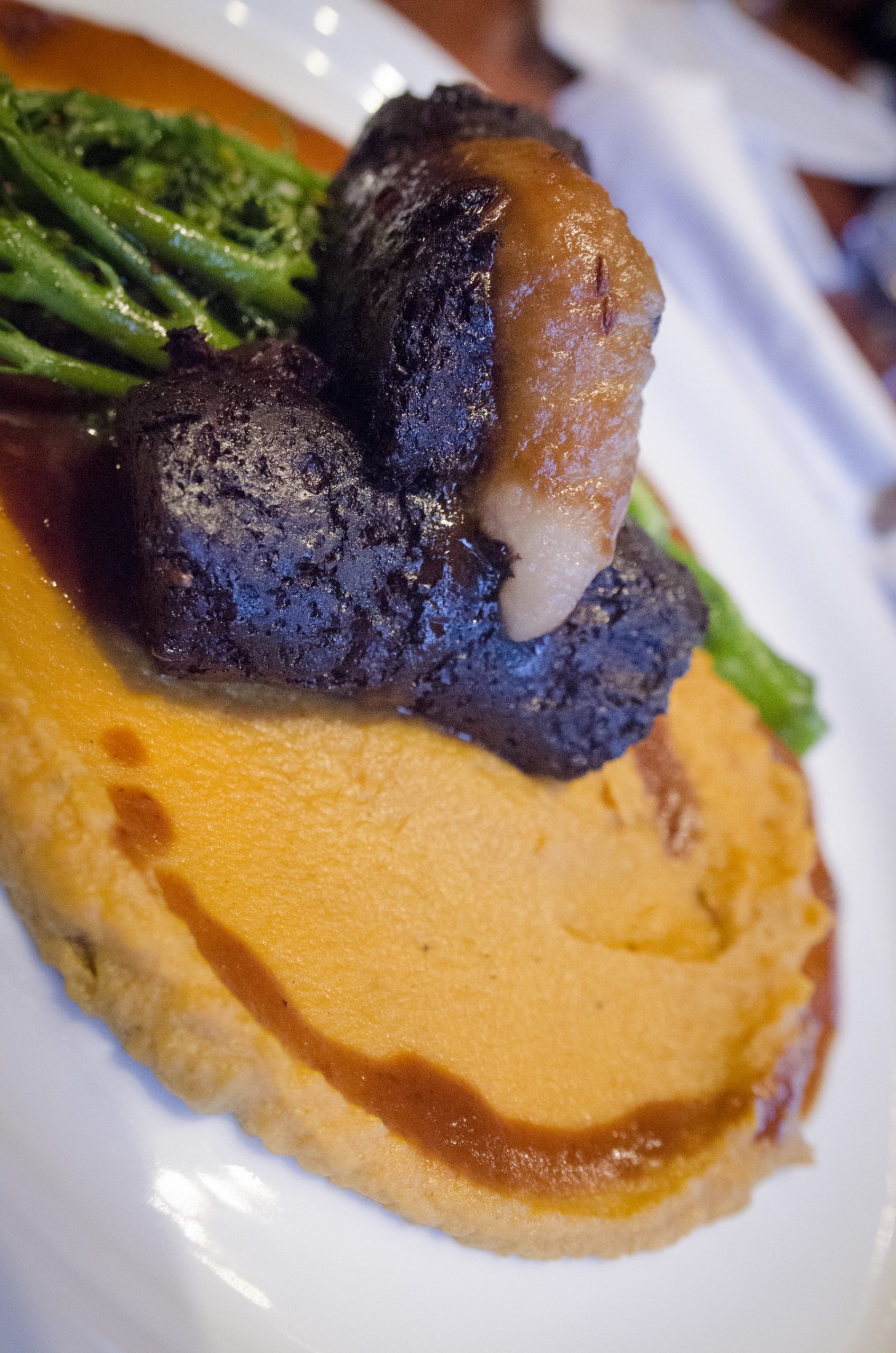 Morceau de boudin poêlé disposé sur une purée lisse.