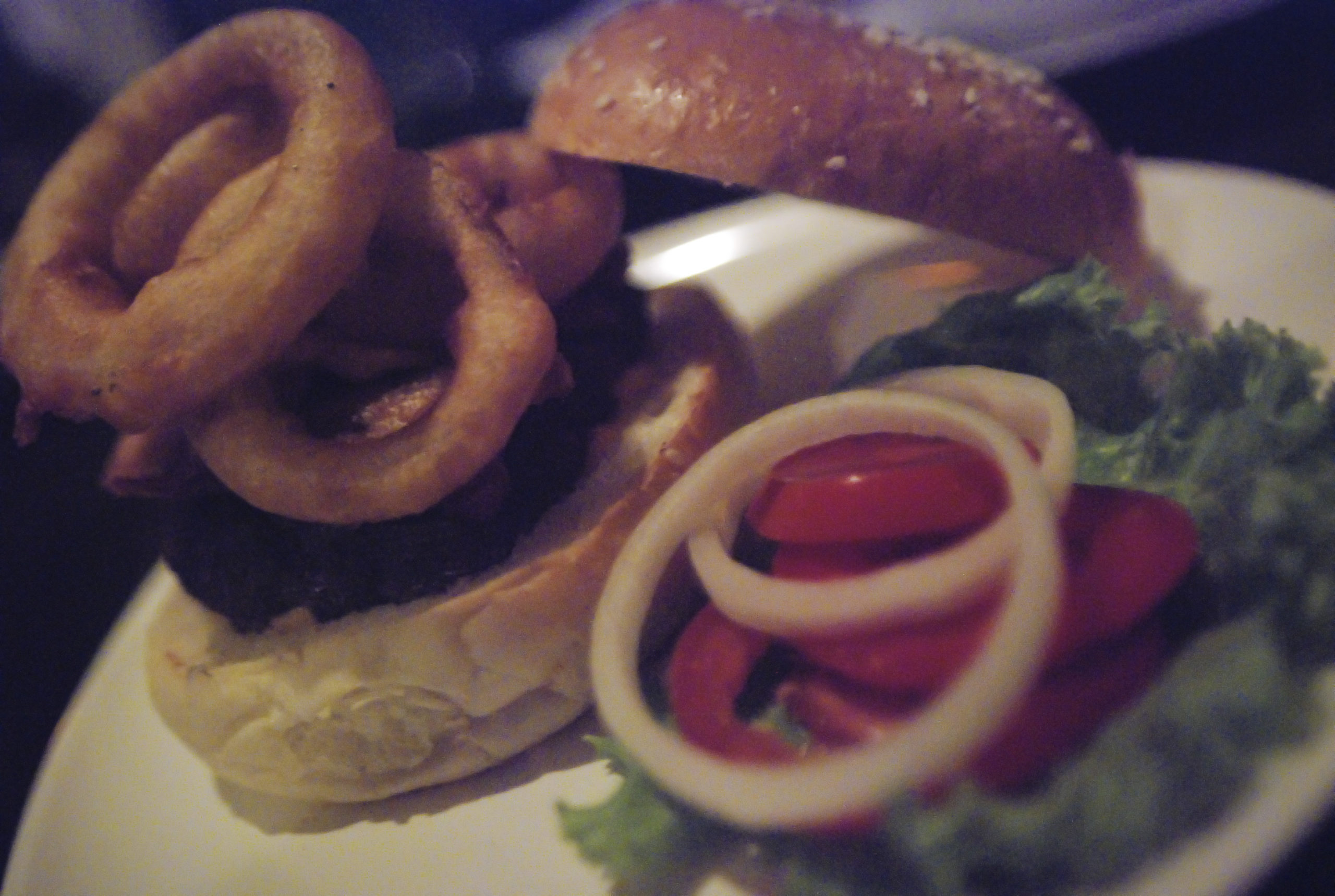 Gros sandwich garni de viande et d'épaisses rondelles d'oignon frites.