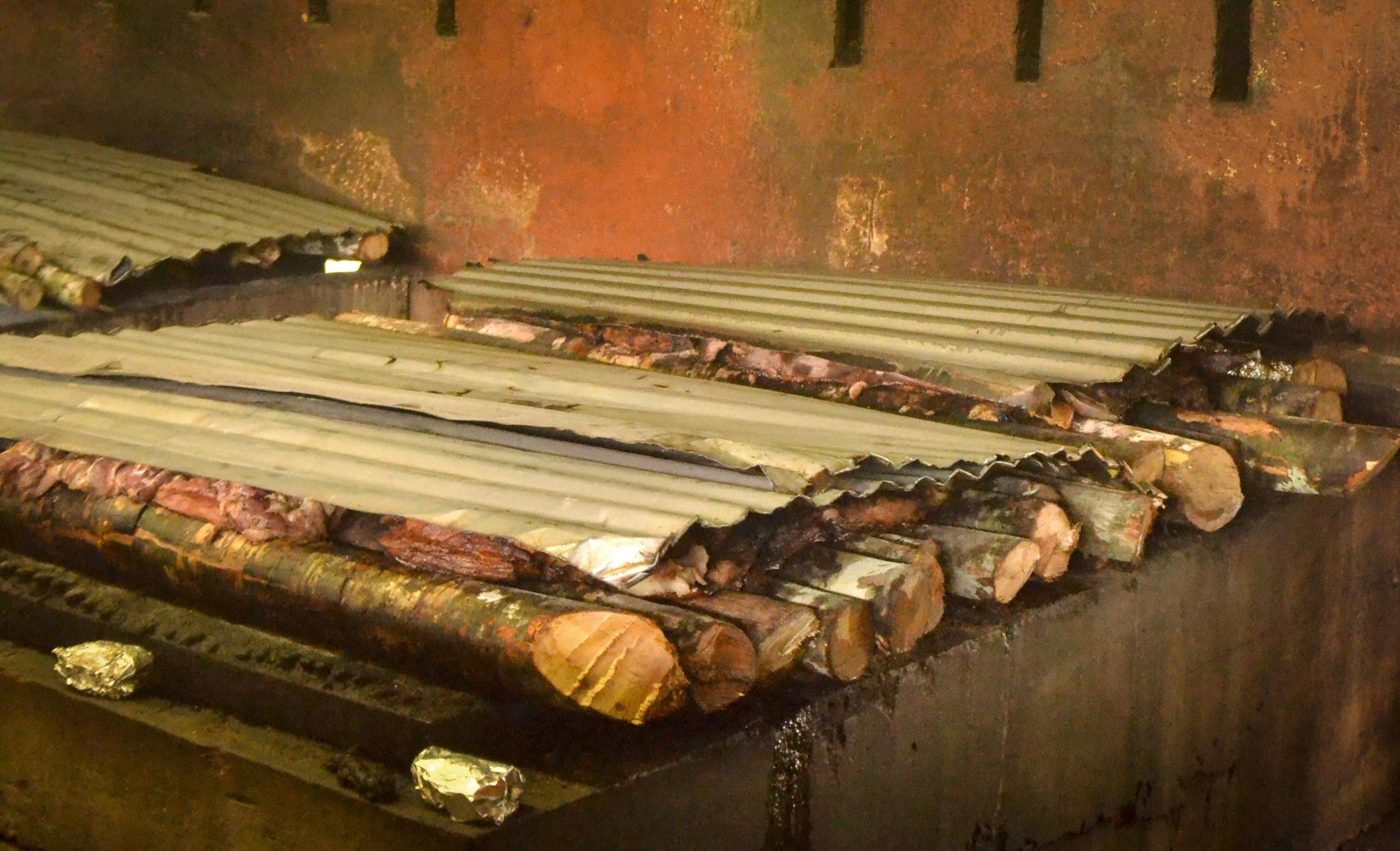 Morceaux de viande rôtissant lentement sur des braises et du bois de piment.