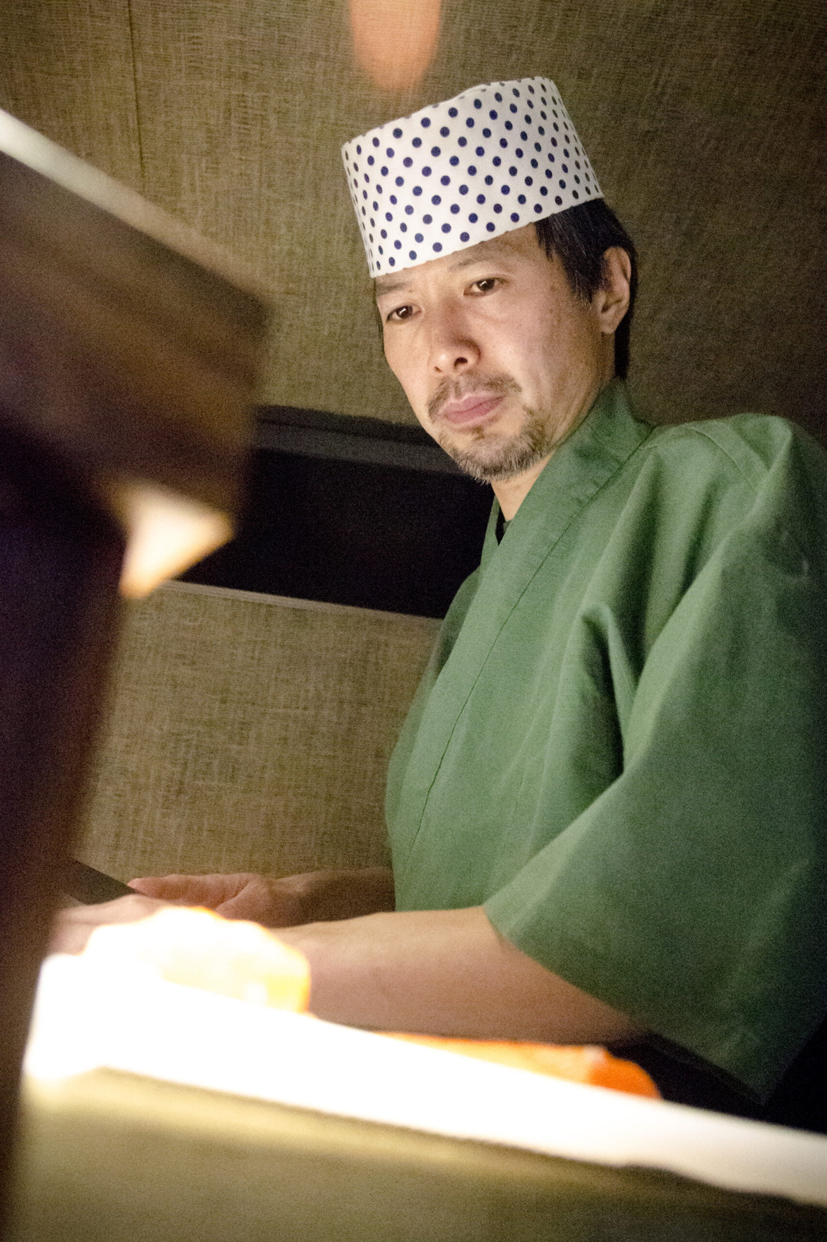 Le chef japonais concentré préparant du poisson avec son couteau.