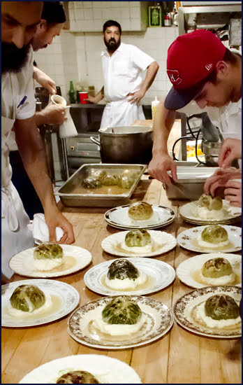 Chefs plating seasoned pork wrapped in a cabbage leaf with potato purée