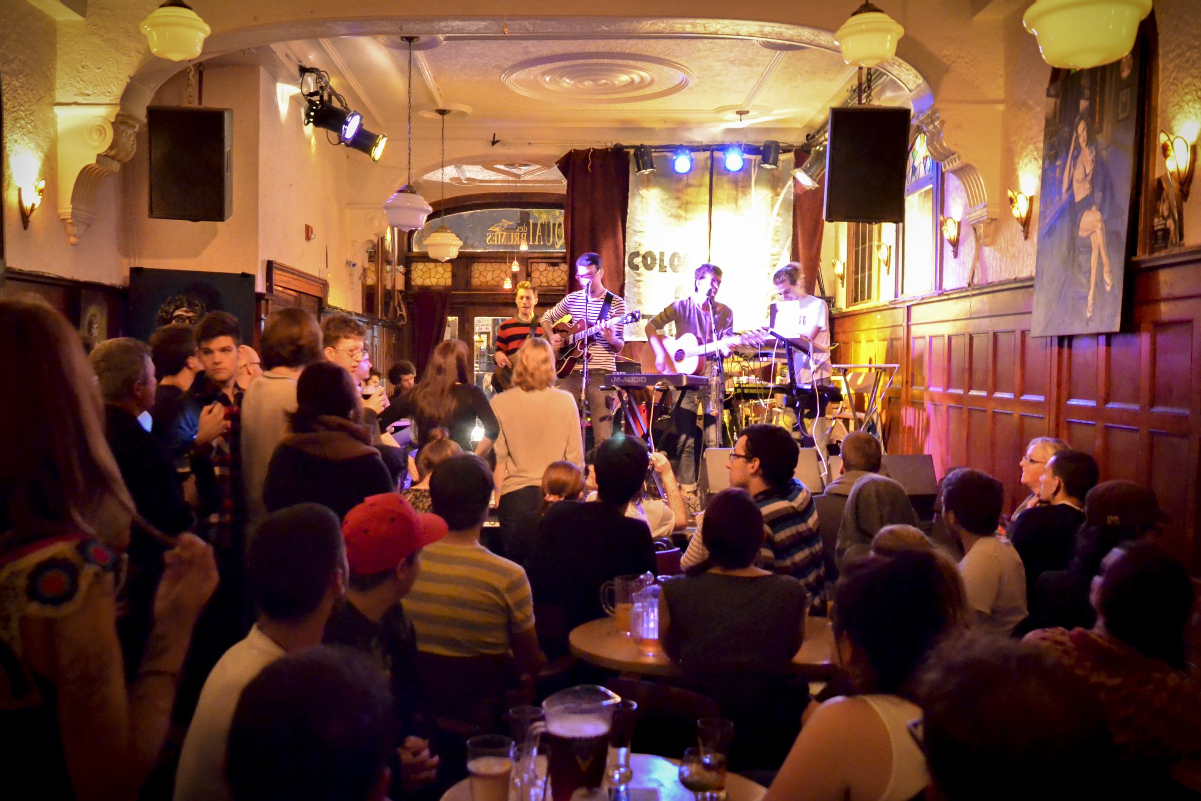 Musiciens jouant passionnément sur la petite scène d'un bar bondé.