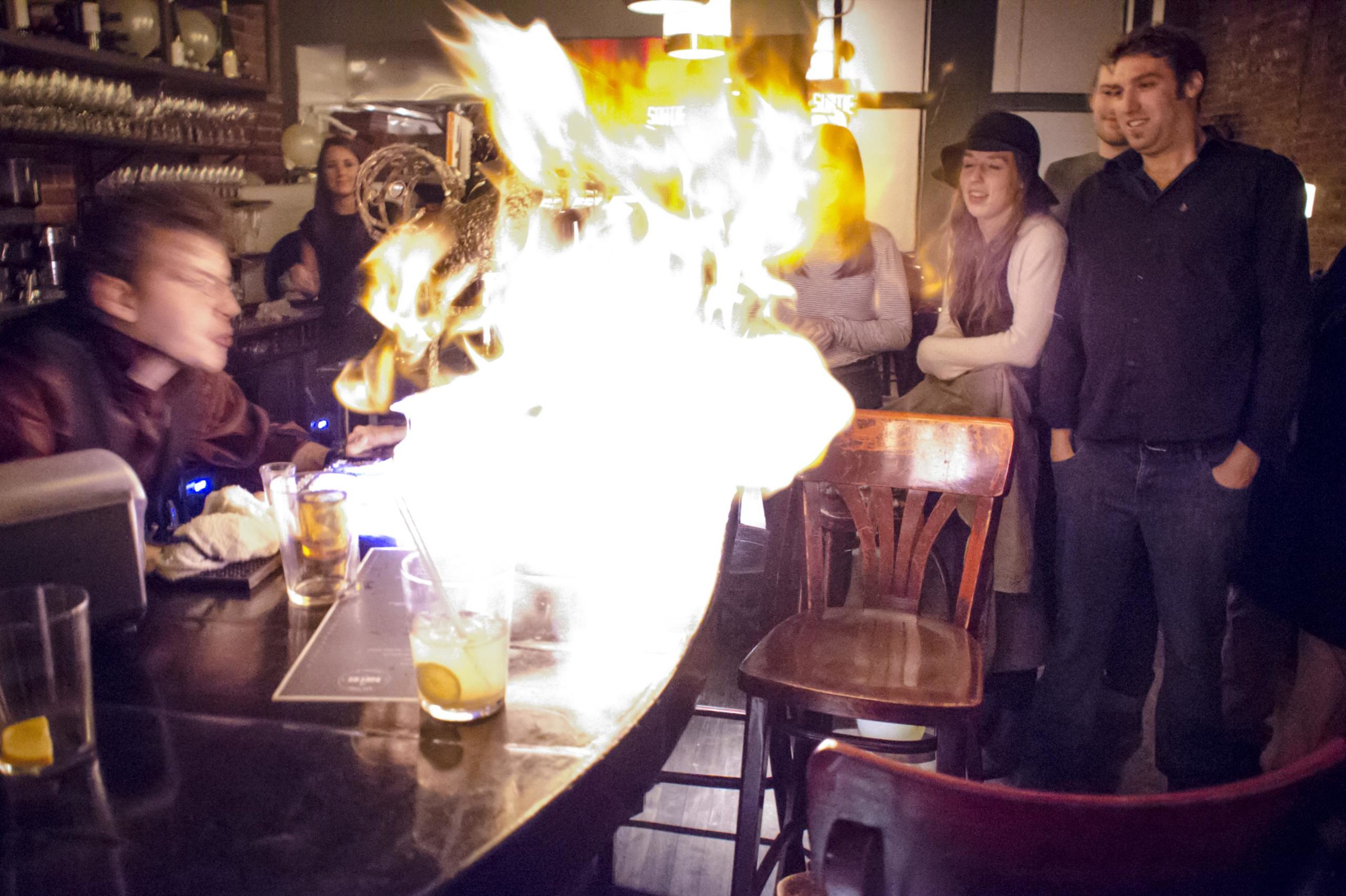 Le barman verse un alcool brûlant qui illumine le bar de ses flammes.