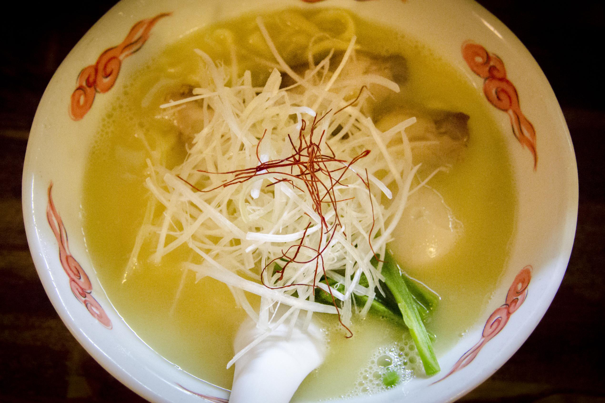 Bouillon jaune laiteux contenant des nouilles et des morceaux de volaille effilochés.