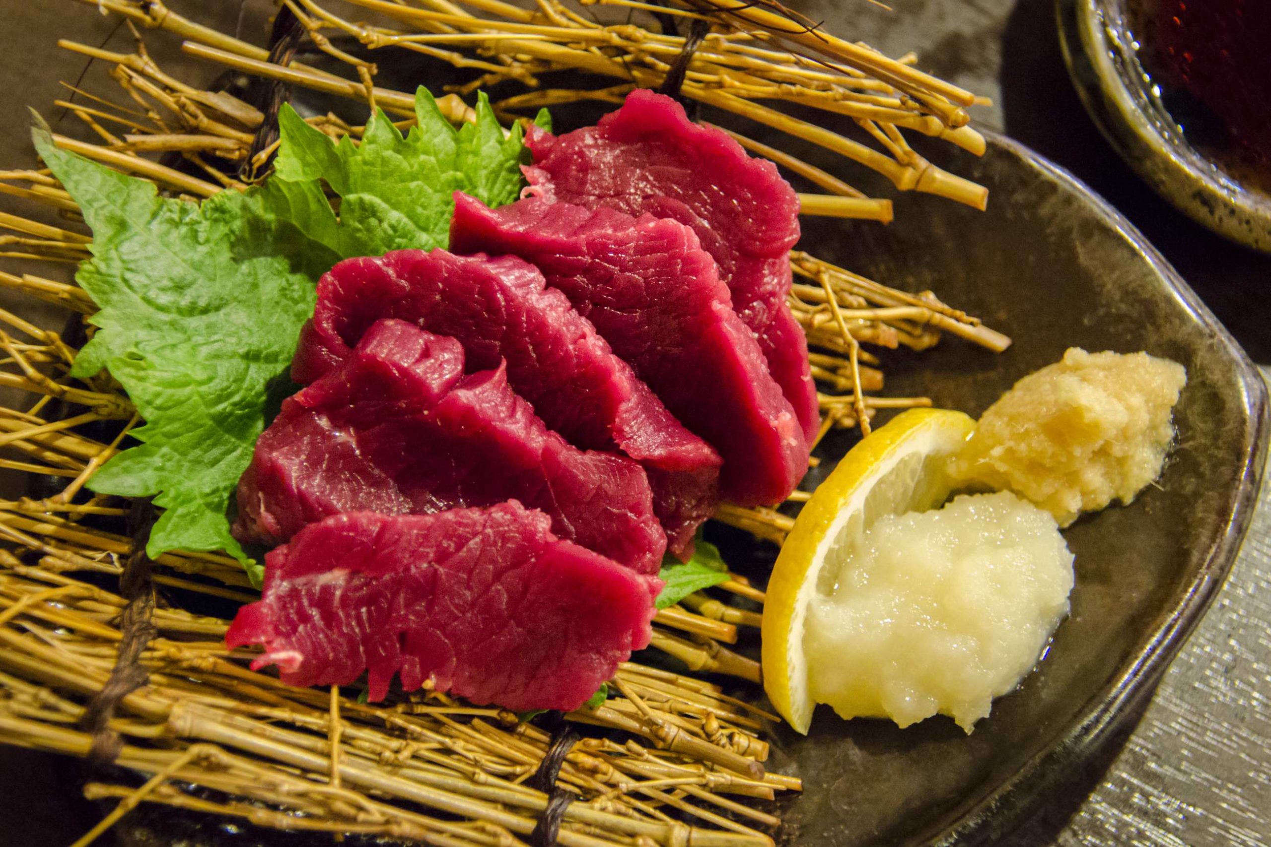 Fines tranches de viande rouge vif crues servies avec de l'ail et du gingembre.