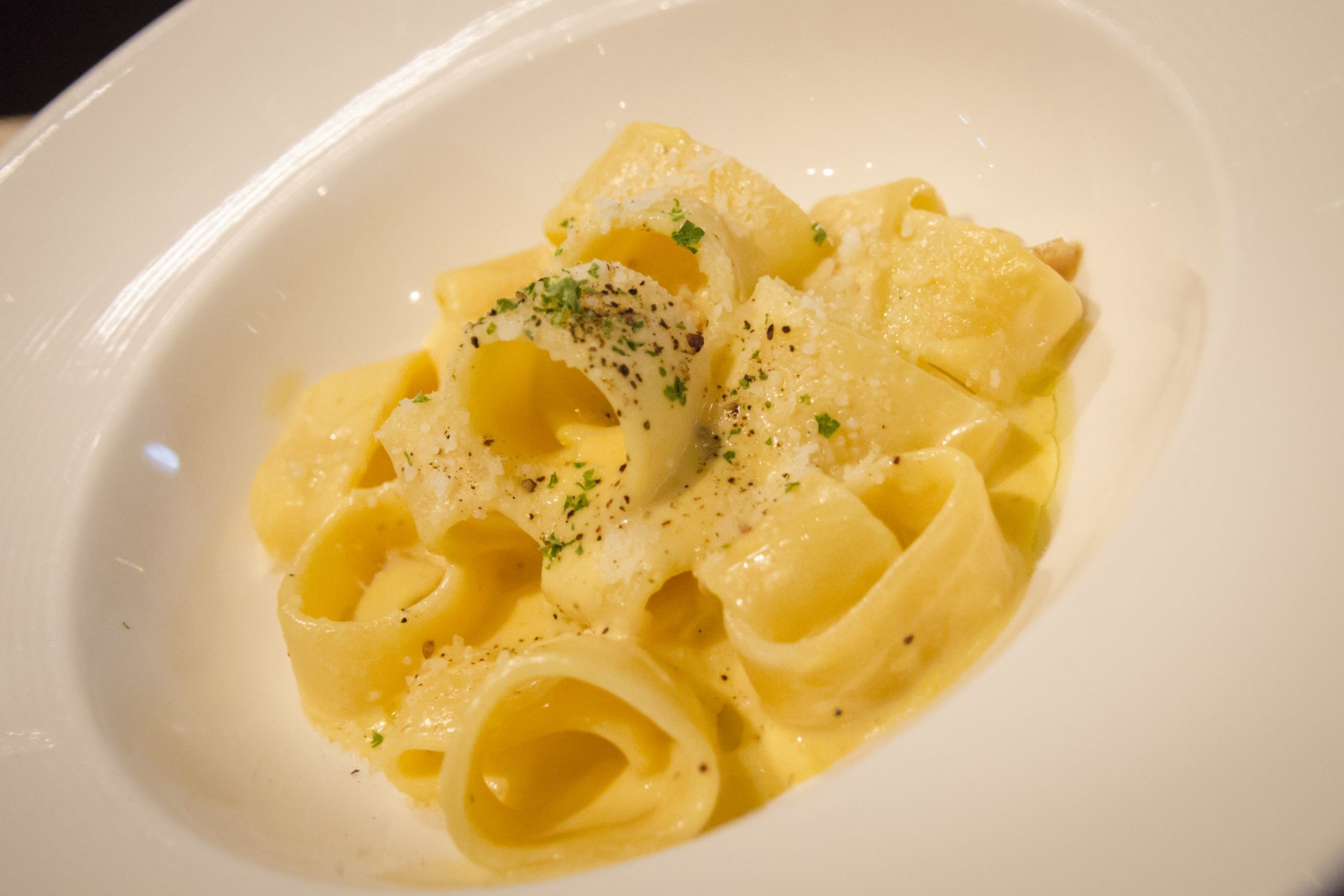 Assiette de spaghettis enrobés d'une sauce onctueuse au jaune d'œuf et de guanciale.