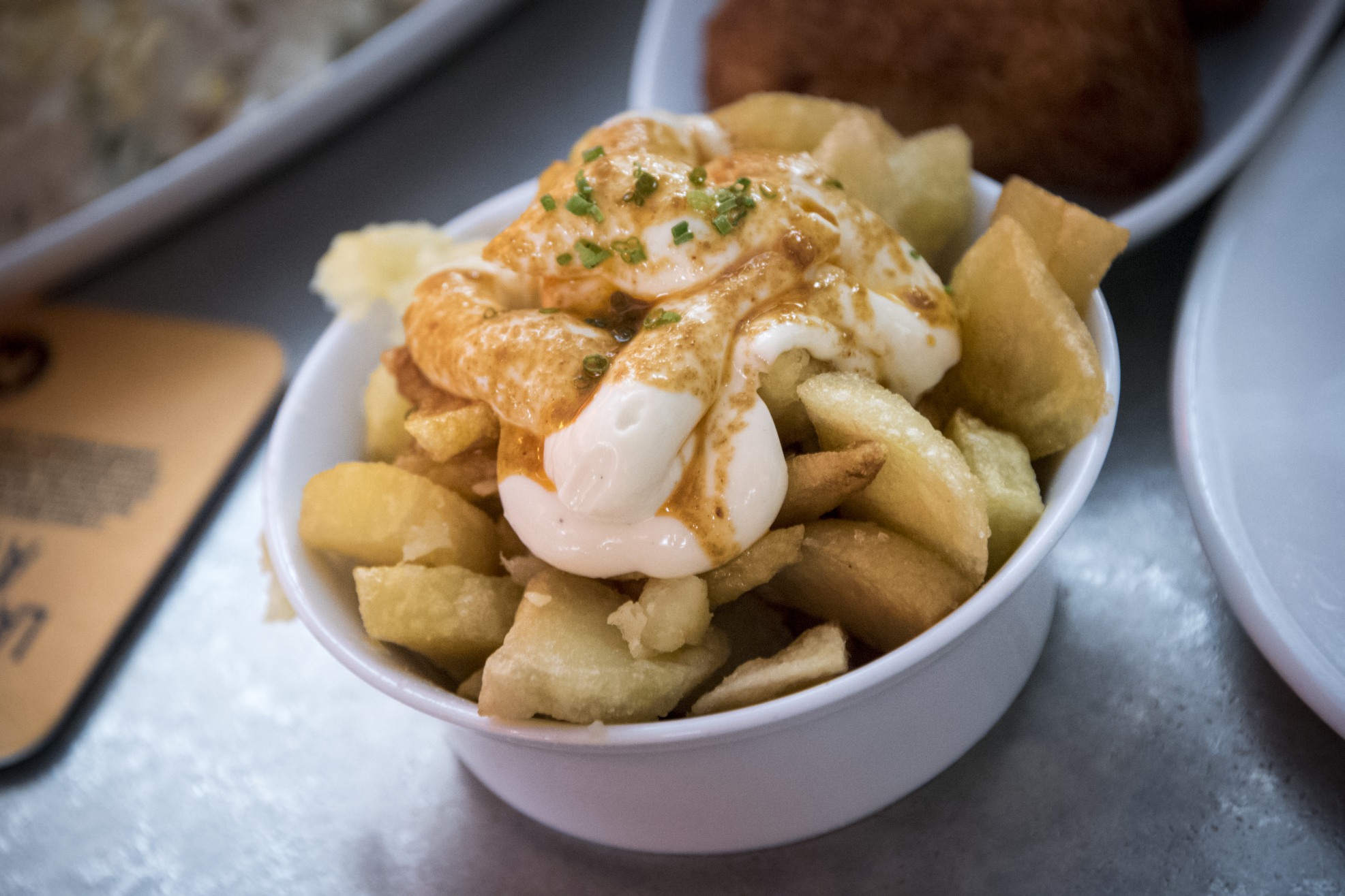 Cubes de pommes de terre frits généreusement recouverts de sauce rouge épicée.