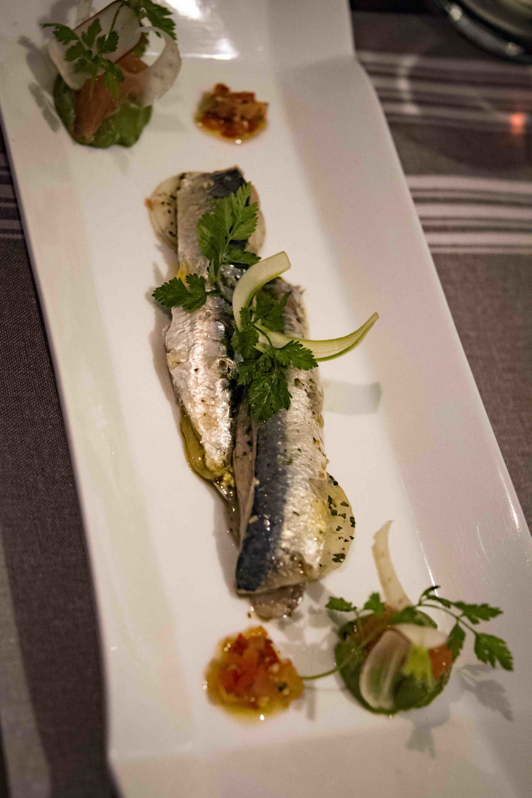Poissons argentés entiers alignés soigneusement dans une assiette d'accompagnement.