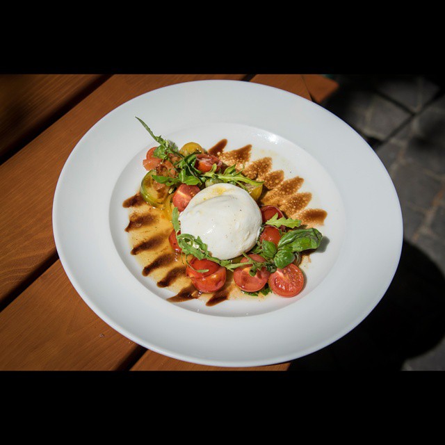 Things to do in Basel - Volkshaus in Basel has a stunningly beautiful terrasse for those spring and summer lunches. And the food is great, too! This is a burrata and tomato salad with natural sunlight!