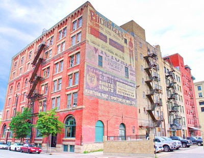 red brick building with old painted signs and fire escapes in the Exchange district of Winnipeg - photo by Dave Shaver under CC BY 2.0